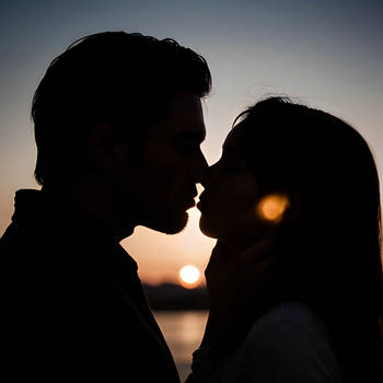 A couple kissing against the backdrop of sunset 