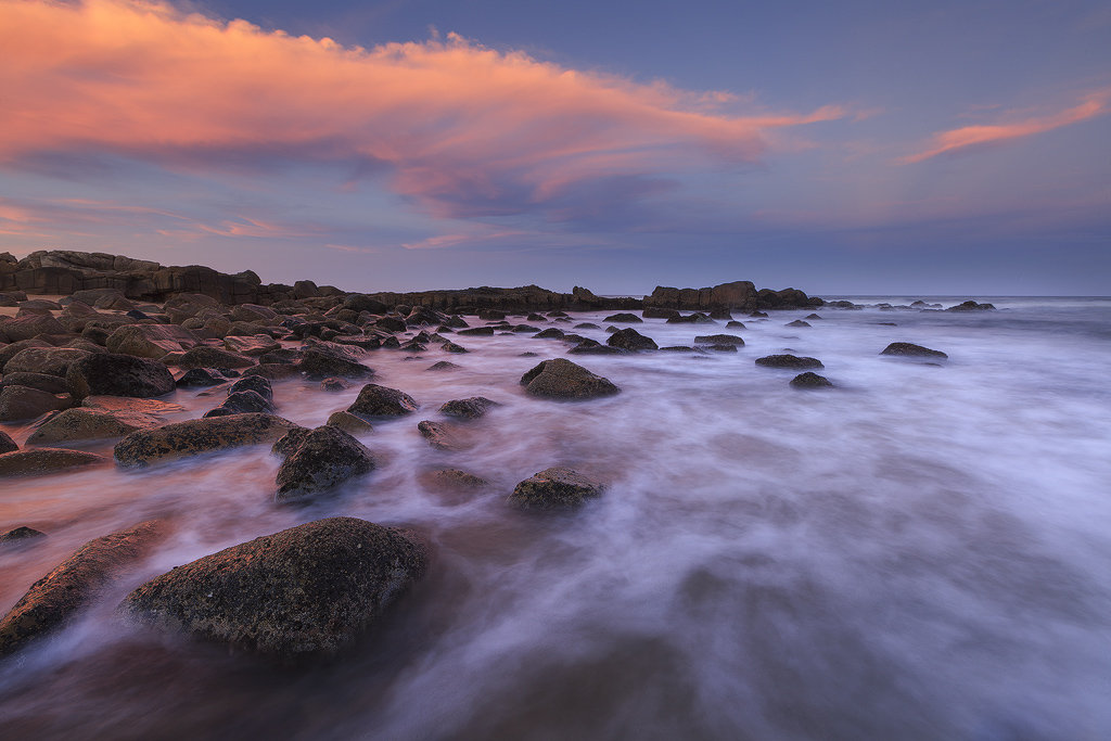 Pink and Blue and a beach with some Rocks