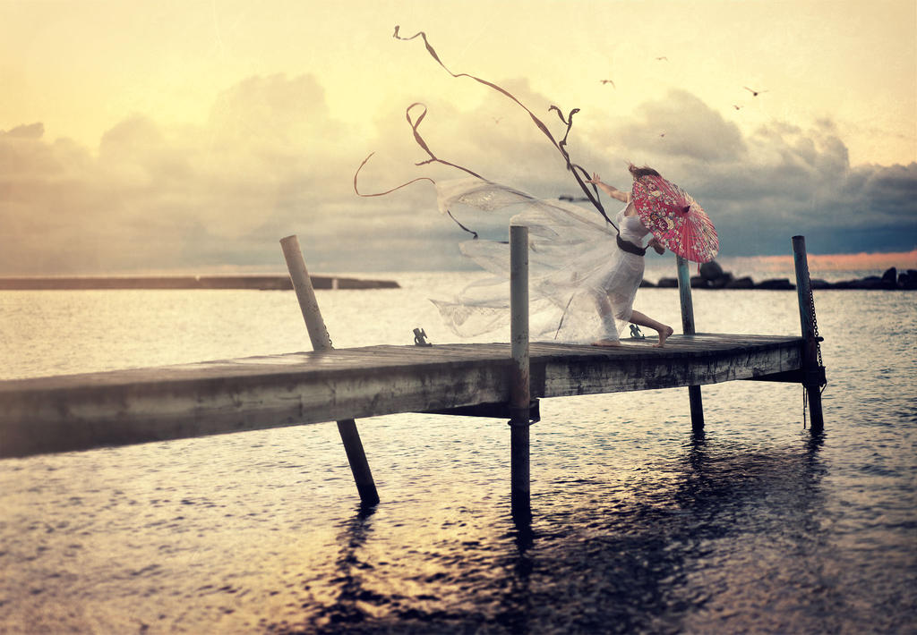 White Dress with Red Umbrella Blowing over Water