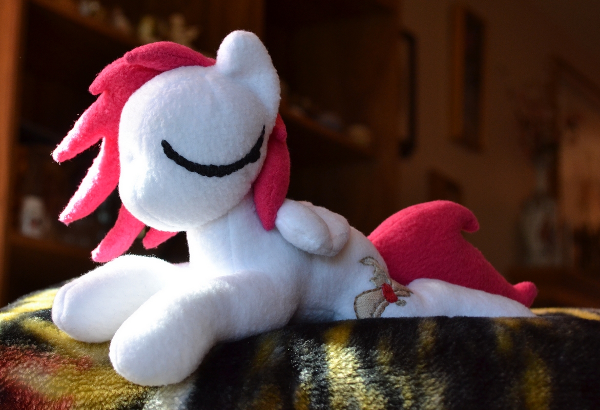 Phoe plushie napping in a sunbeam