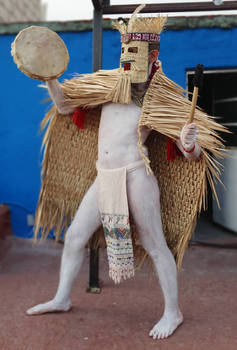 mexica man in rain cape playing drum