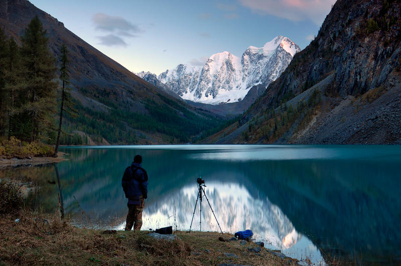 В горах станут воды. Озеро на вершине горы. Человек в горах. Фотограф пейзажист горы. Человек у горного озера.