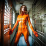 Scared women in orange latex catsuit in prison cel