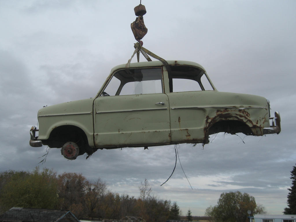 wrecked car suspended over junkyard