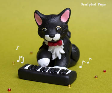 Tuxedo cat playing music sculpture