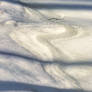 A riverbank gradually reappearing under snow