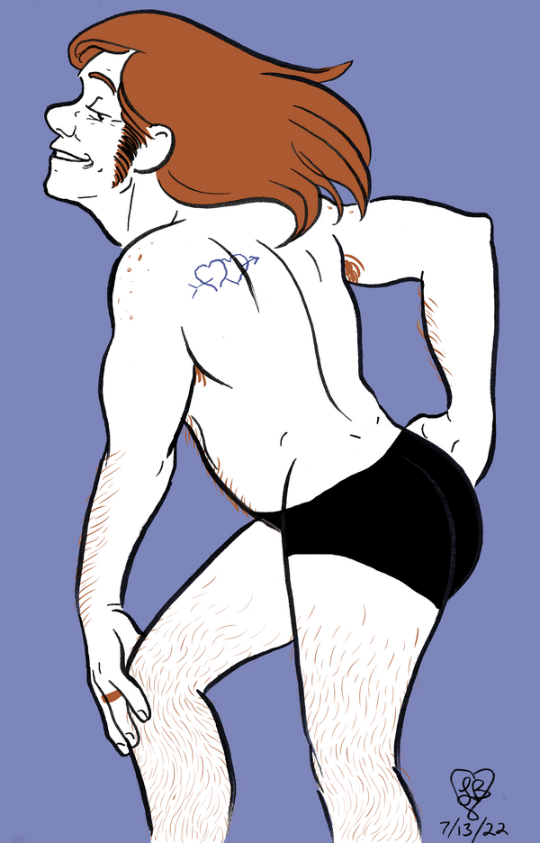 Mac in black booty shorts, striking a glamorous pose and flipping his hair.