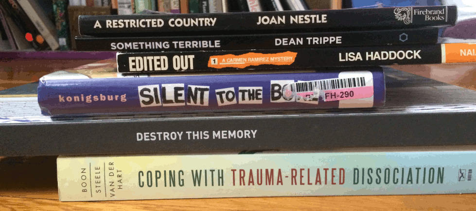 Books stacked so their spines line up, making a poem: A Restricted Country / Something Terrible / Edited Out / Silent to the Bone / Destroy this Memory / Coping with Trauma-Related Dissociation