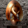 Sculpture in rolled copper with old brick wall.