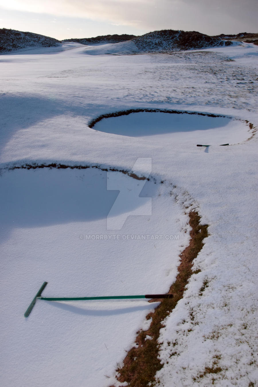 rakes in bunker on a snow covered link golf course