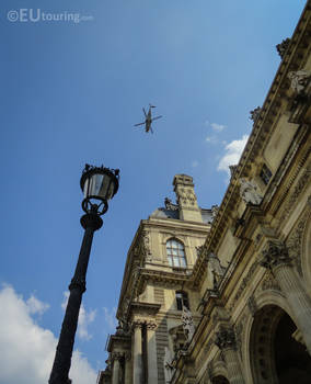 Helicopter passing over architecture of the Louvre