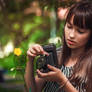 Girl with antique camera staying by a flower