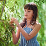 Girl in blue dress staying near a osier
