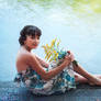 Girl in dress sitting by a lake