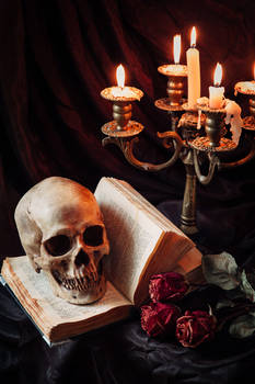 Human skull on book with antique candlestick