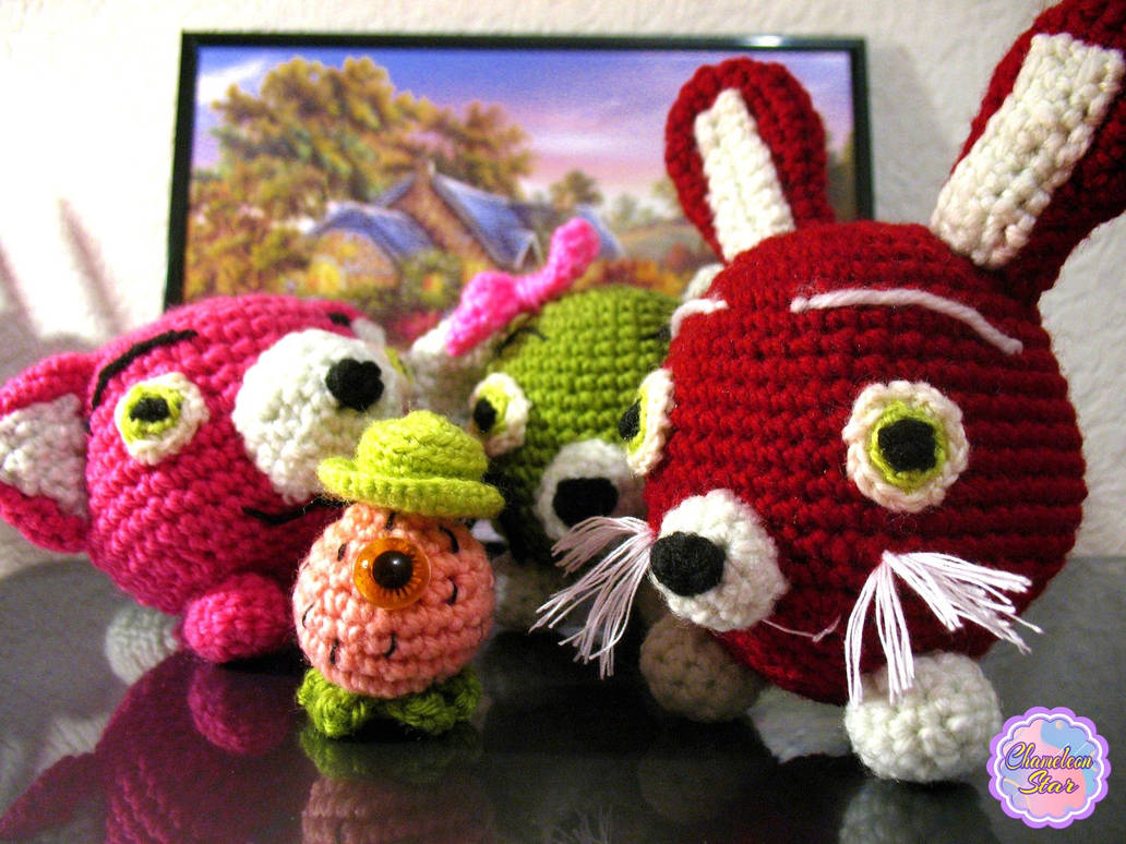 A photo of handmade crochet amigurumi burgundy red rabbit, grassy green cat, magenta pink fox and pink Mr. Strawberry