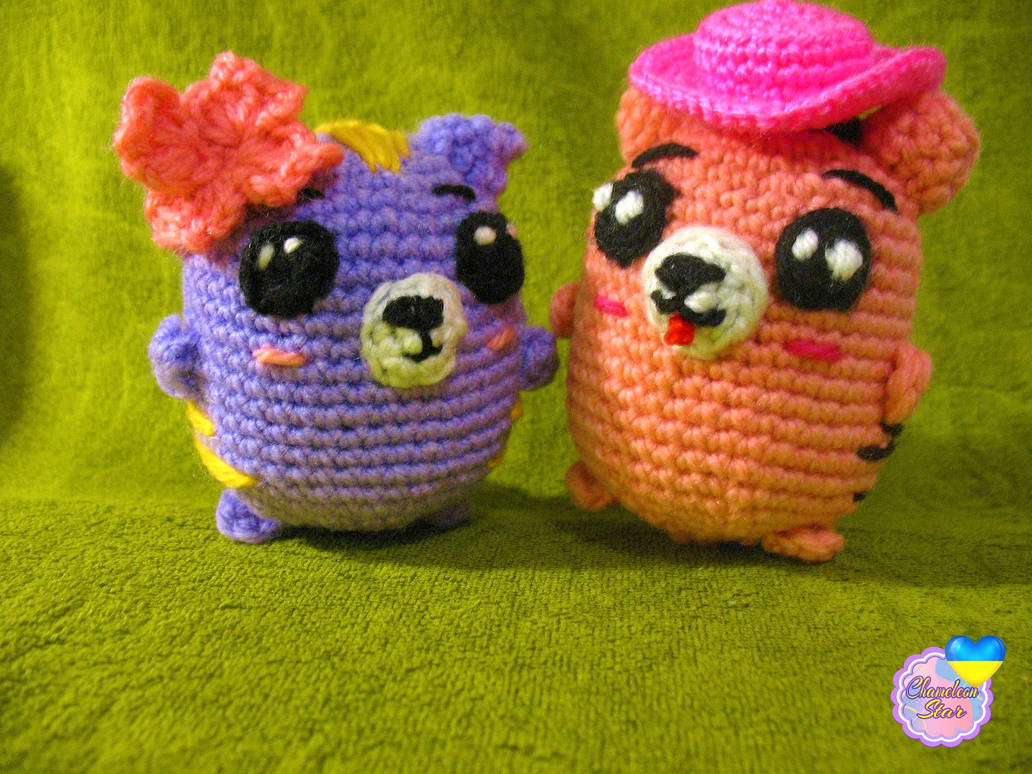 A photo of handmade crochet amigurumi lilac cat named Tara and a pink cat called Aisling, who are a part of a big Tororo Puss family