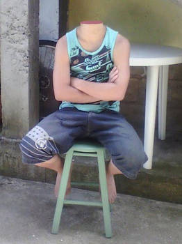 Headless boy with crossed arms sitting on stool