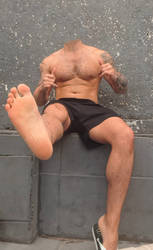 Headless shirtless man showing sole of foot