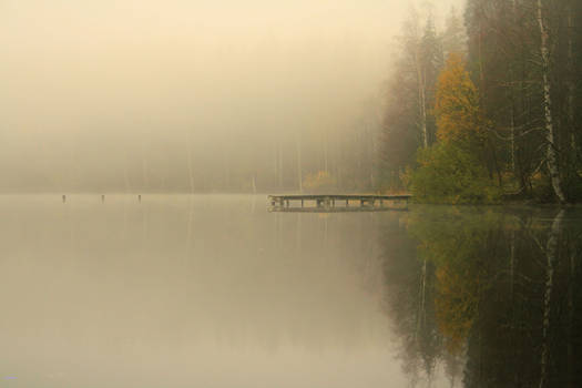 Lonely pier on the foggy lake