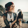 Pirate woman holding a bird near seashore