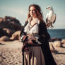 Pirate woman holding a bird near seashore