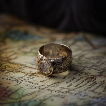 Traveler's jewelry compass ring, lying on a map