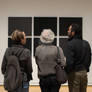 People looking at black squares in modern gallery