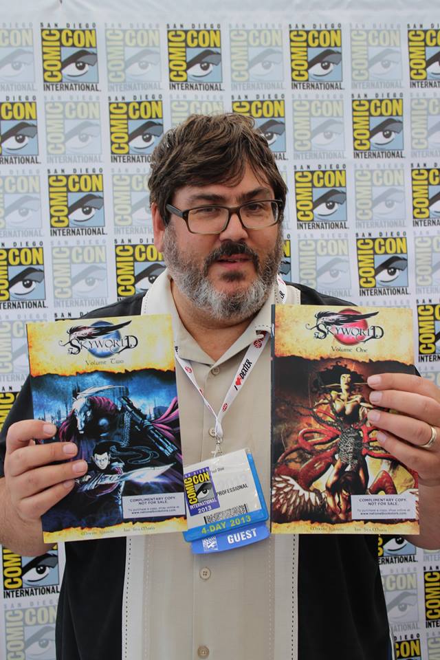 Paul Dini holding Skyworld vol 1 and 2