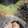 A small rainbow at the base of a waterfall