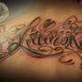 Chicano lettering back tattoo