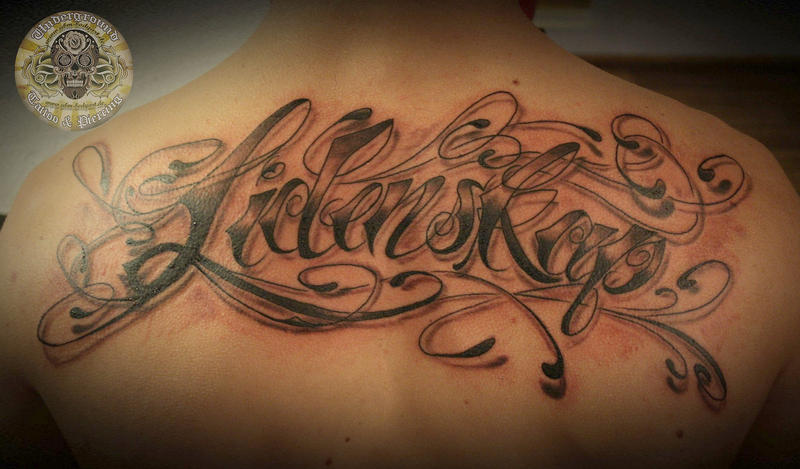 Chicano lettering back tattoo