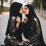 Two muslim girls in shiny abayas and hijab kissing