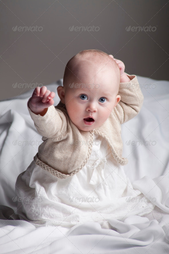 Baby Girl Sitting in White Bed Sheets