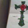 A cross with a rose with vines wraped around it